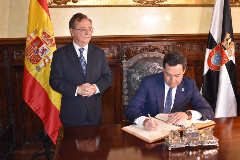 Juanma Moreno firmando en el Libro de Honor